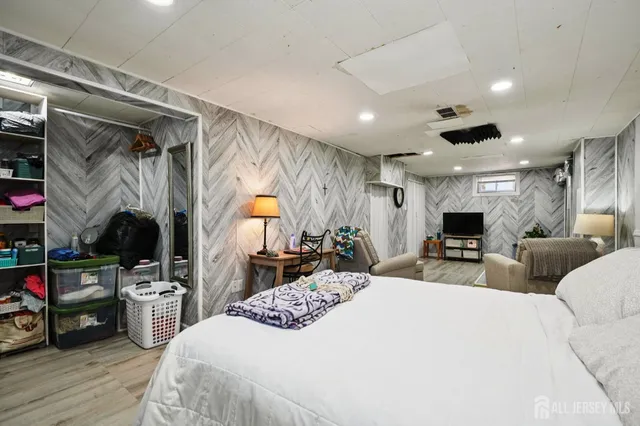 a large bedroom with bed and a large mirror on the dresser