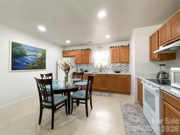 a kitchen with stainless steel appliances kitchen island granite countertop a table chairs sink and cabinets