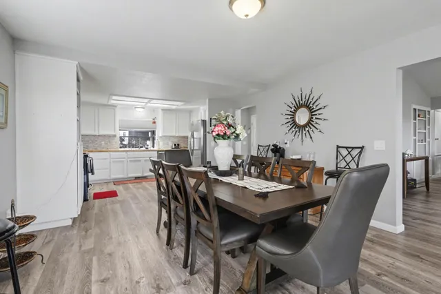 a kitchen with stainless steel appliances a refrigerator a stove a dining table and chairs with wooden floor