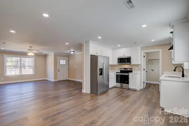 an empty room with windows and chandelier fan