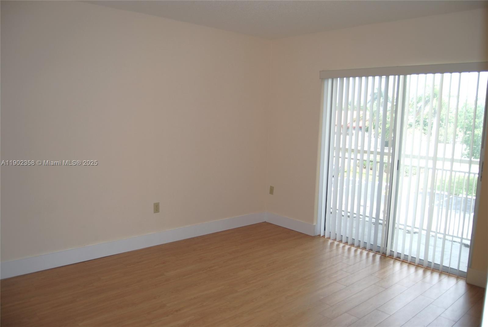 8540 Southwest 212th Street, Unit 203 Cutler Bay, FL 33189 - Photo 16 of 29 a view of an empty room with wooden floor and a window