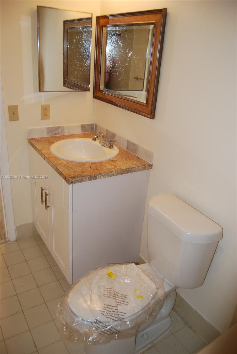 8540 Southwest 212th Street, Unit 203 Cutler Bay, FL 33189 - Photo 19 of 29 a bathroom with a granite countertop toilet and a sink