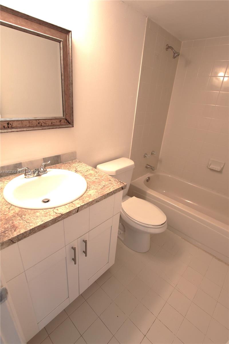 8540 Southwest 212th Street, Unit 203 Cutler Bay, FL 33189 - Photo 25 of 29 a bathroom with a granite countertop sink a toilet and a bathtub