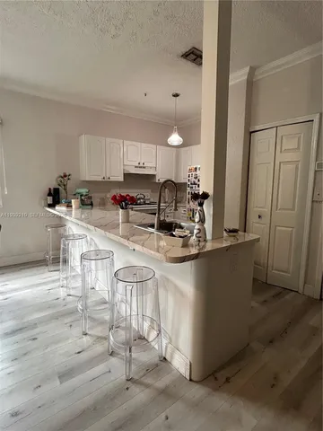 a kitchen with stainless steel appliances granite countertop a stove a sink a refrigerator and white cabinets with wooden floor