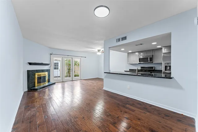 a view of an empty room with window and wooden floor