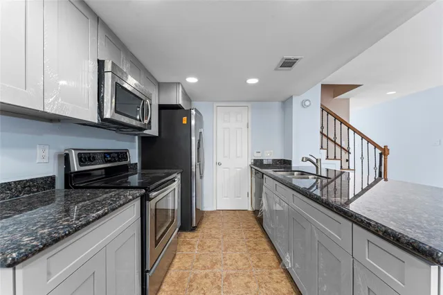 a kitchen with stainless steel appliances granite countertop a stove a sink and a refrigerator
