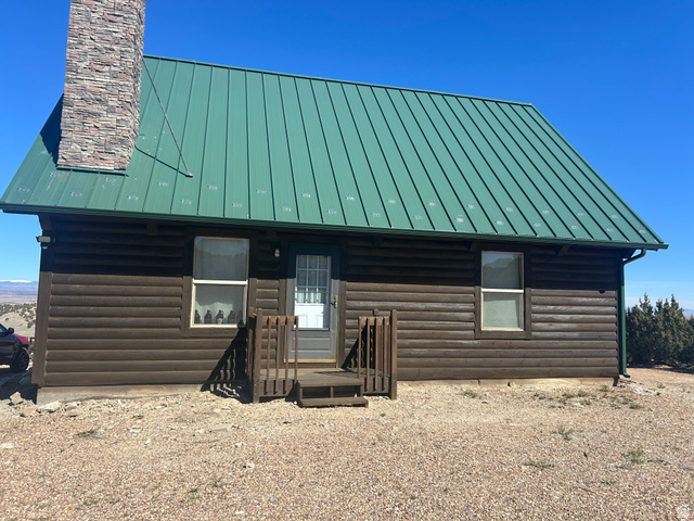 19075 West Honesty Cove Duchesne, UT 84021 - Photo 3 of 44 Log cabin exterior featuring a green metal roof, stone chimney, and wood siding
