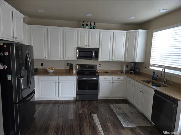 a kitchen with granite countertop a refrigerator stove and sink with wooden floor