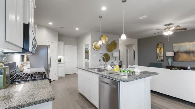 a kitchen with stainless steel appliances granite countertop a sink a stove and a wooden floors