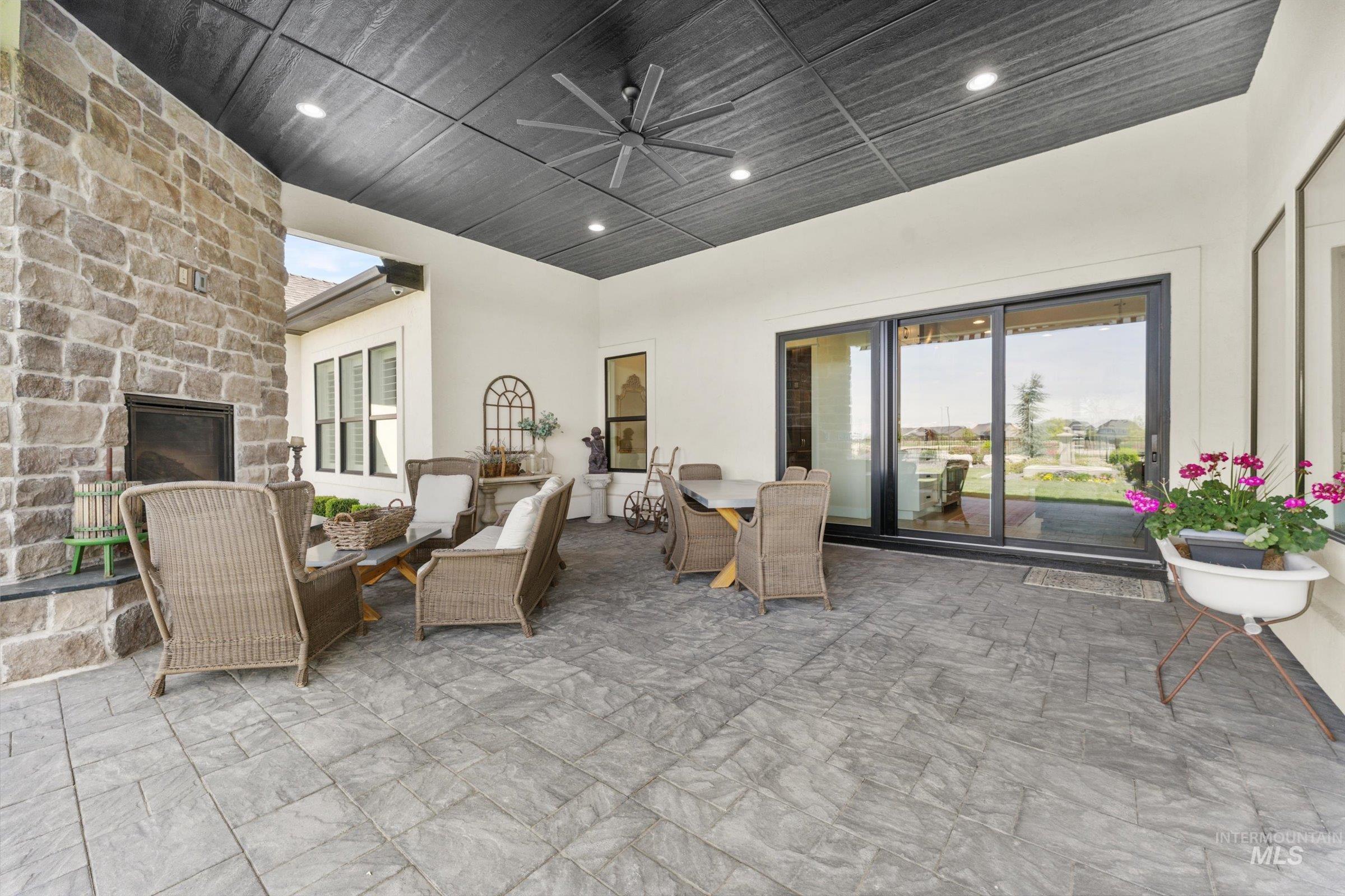 6585 South Pemberley Way Meridian, ID 83642 - Photo 39 of 43 Covered patio featuring a stone-clad fireplace and a dark paneled ceiling with recessed lighting