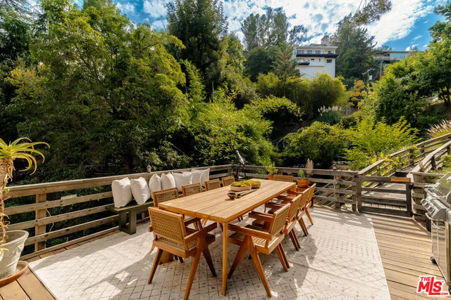 a view of a backyard with couches table and chairs and potted plants