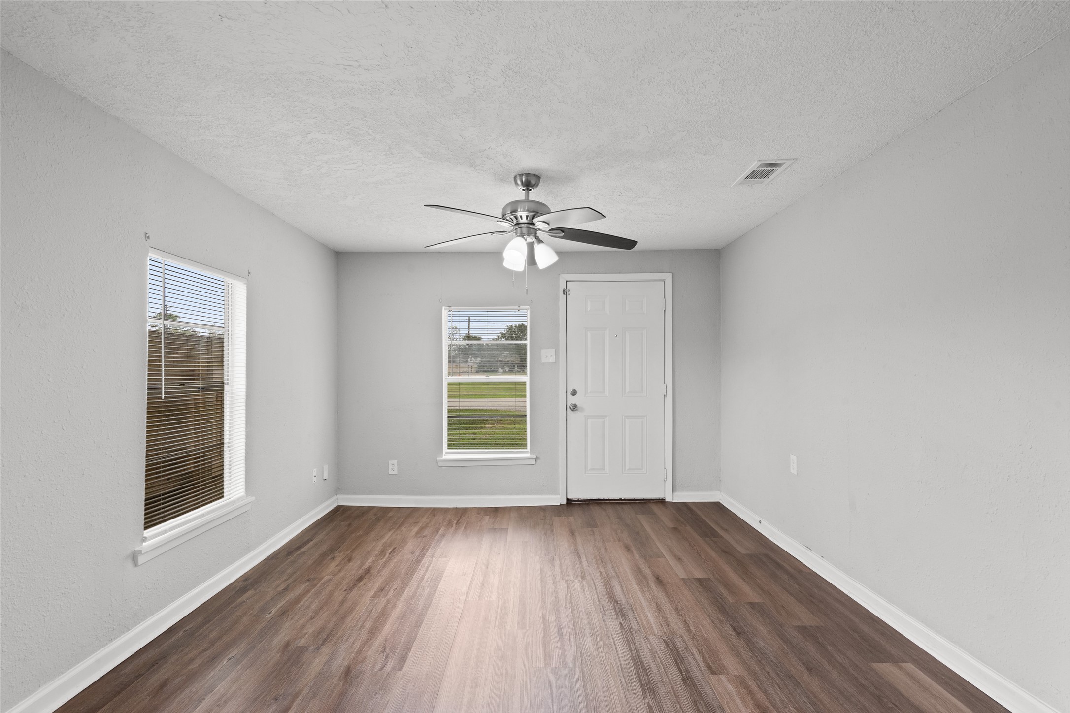 419 North Parrish Street Angleton, TX 77515 - Photo 12 of 25 an empty room with wooden floor chandelier fan and windows