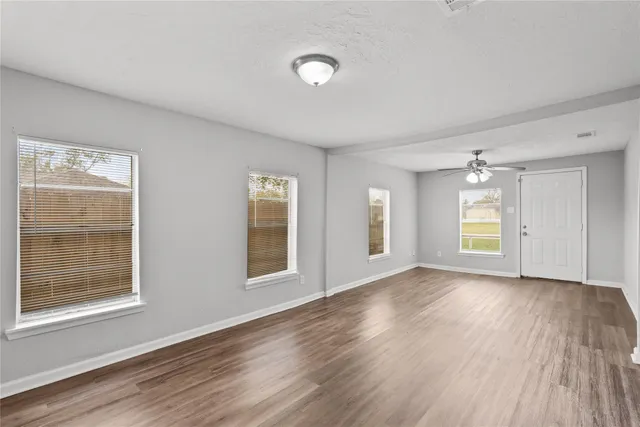 a view of empty room with wooden floor and fan