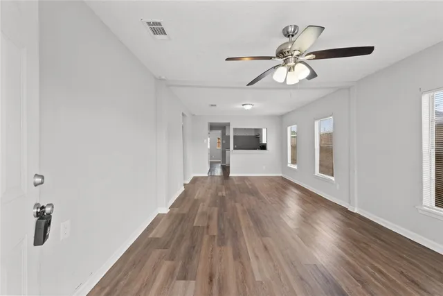 a view of empty room with wooden floor and ceiling fan