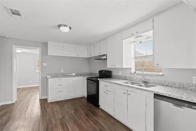 a kitchen that has a sink a stove and cabinets