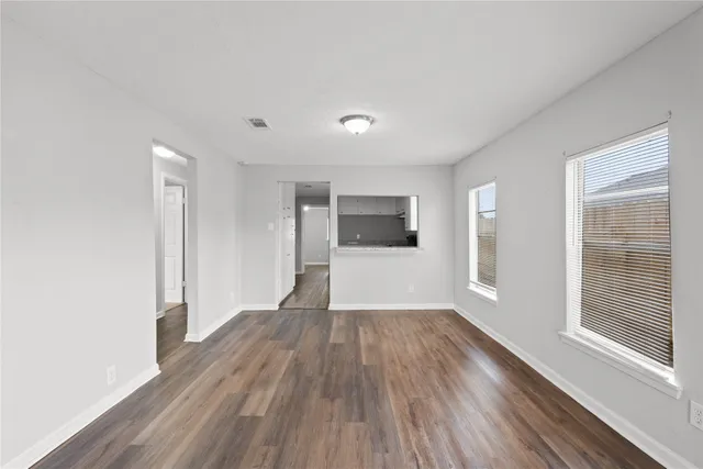 a view of a big room with wooden floor and windows