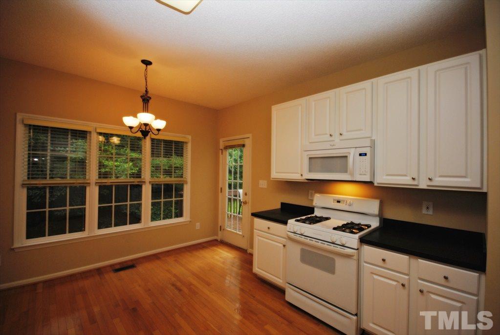 6915 Brigmore Court Raleigh, NC 27617 - Photo 12 of 25 a kitchen with granite countertop a stove a sink and white cabinets