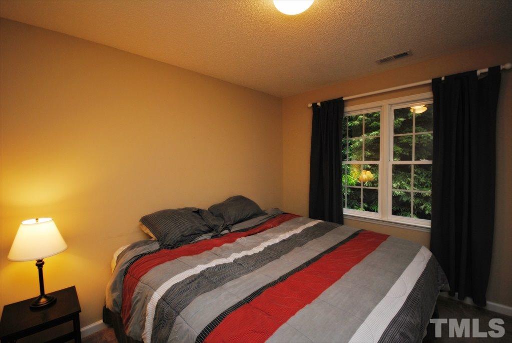 6915 Brigmore Court Raleigh, NC 27617 - Photo 18 of 25 a bedroom with a bed and a lamp