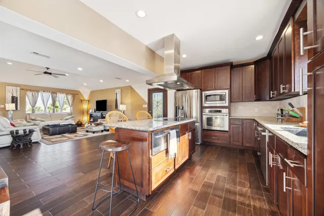 a large kitchen with stainless steel appliances kitchen island granite countertop a large center island and a stove