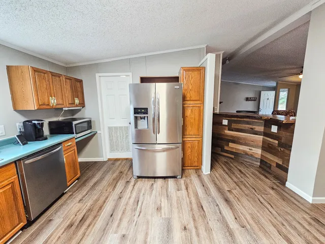 a kitchen with stainless steel appliances a refrigerator a stove top oven and wooden floors