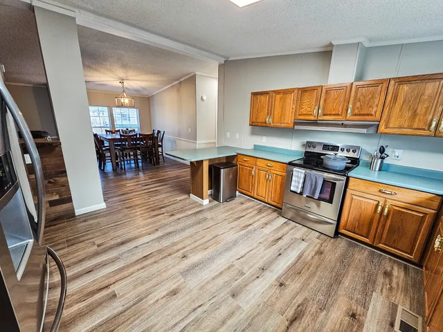 a kitchen with stainless steel appliances wooden floors stove top oven and cabinets