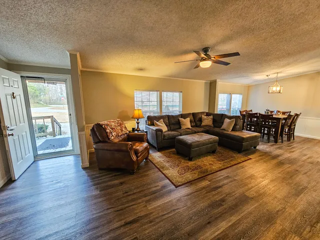 a living room with furniture a large window and wooden floor