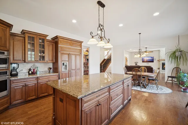 a kitchen with stainless steel appliances granite countertop a stove top oven a sink a dining table and chairs with wooden floor