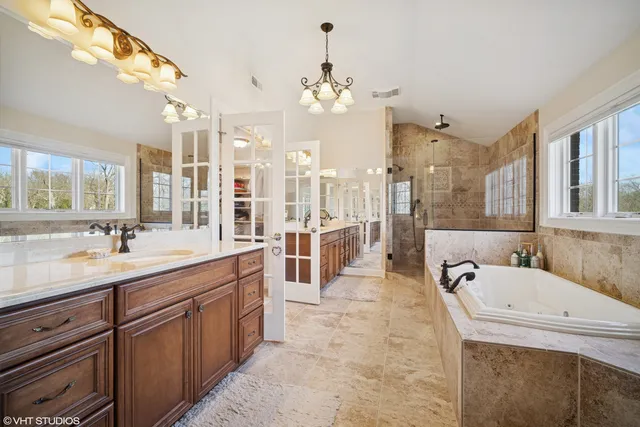 a spacious bathroom with a granite countertop sink a mirror and bathtub