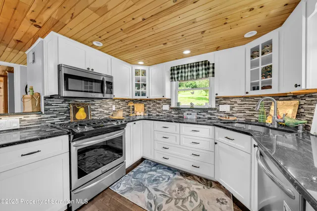 a kitchen with stainless steel appliances granite countertop a stove a sink and a microwave