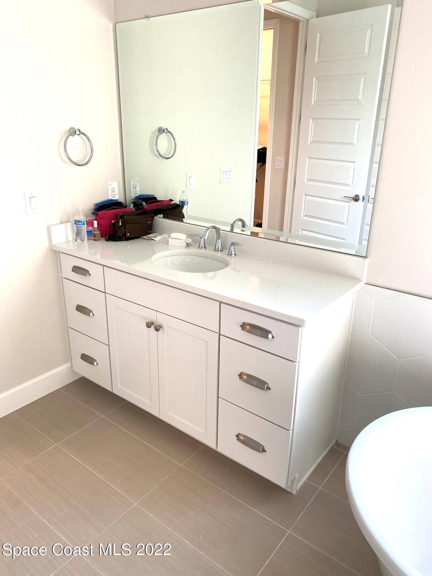 8321 Paragrass Avenue Melbourne, FL 32940 - Photo 19 of 41 a bathroom with a double vanity sink and a mirror