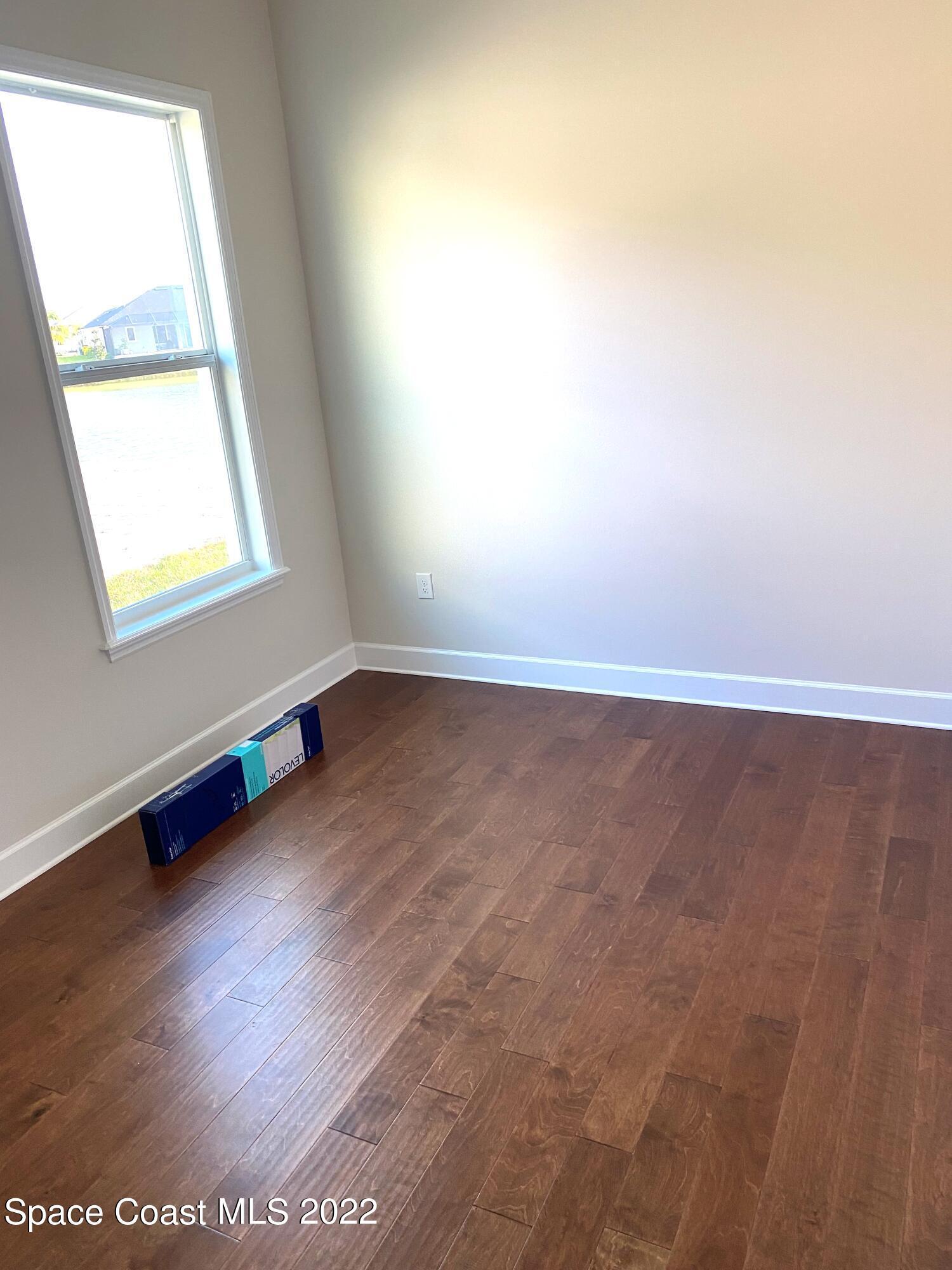 8321 Paragrass Avenue Melbourne, FL 32940 - Photo 27 of 41 an empty room with wooden floor and windows