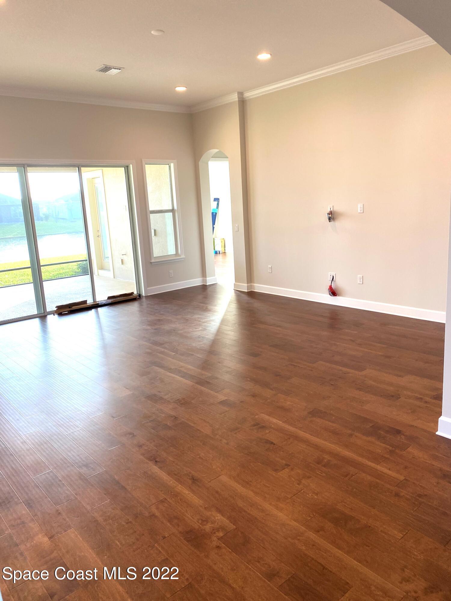 8321 Paragrass Avenue Melbourne, FL 32940 - Photo 9 of 41 an empty room with wooden floor and windows