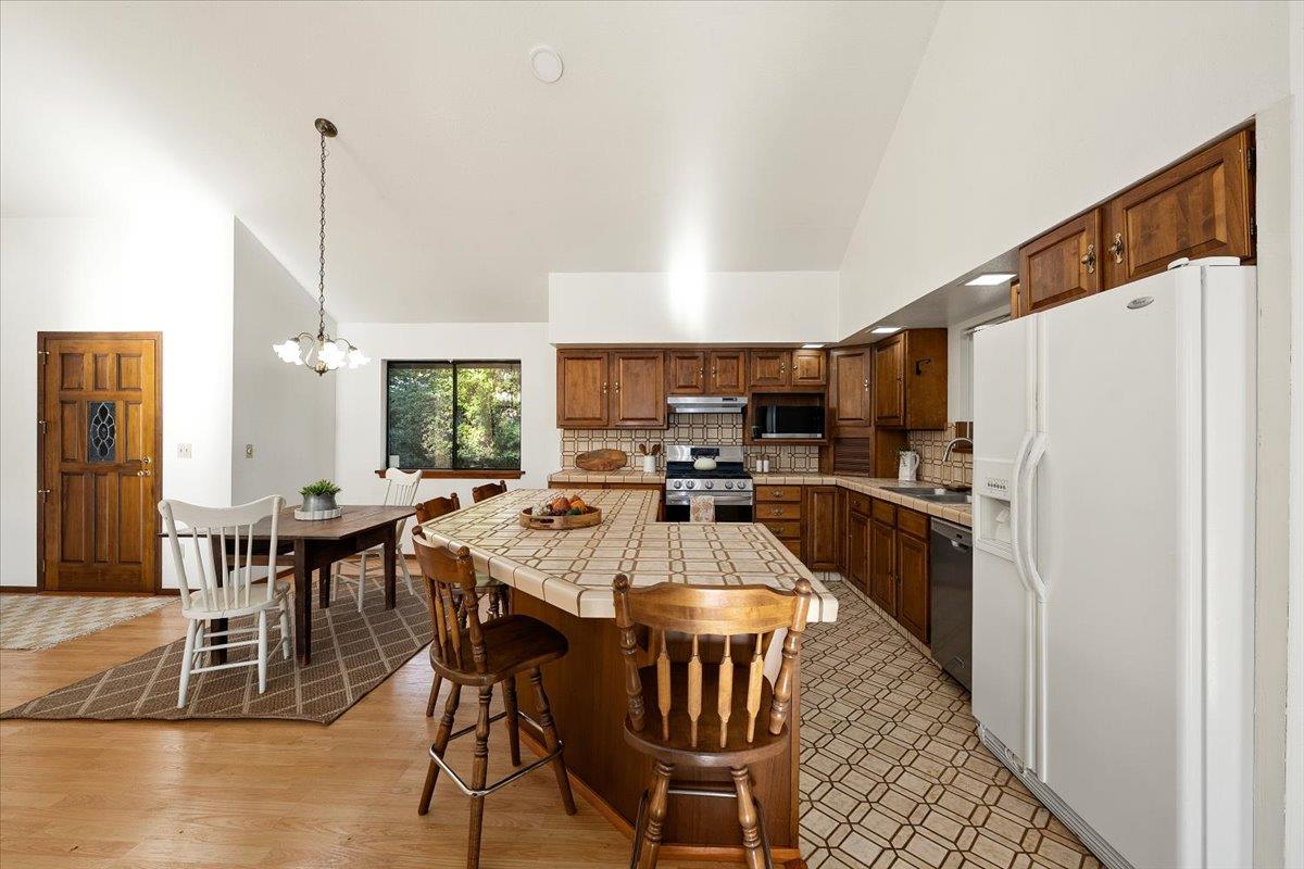 155 Pinewood Way Auburn, CA 95602 - Photo 12 of 92 a kitchen with stainless steel appliances kitchen island granite countertop a dining table chairs and a refrigerator