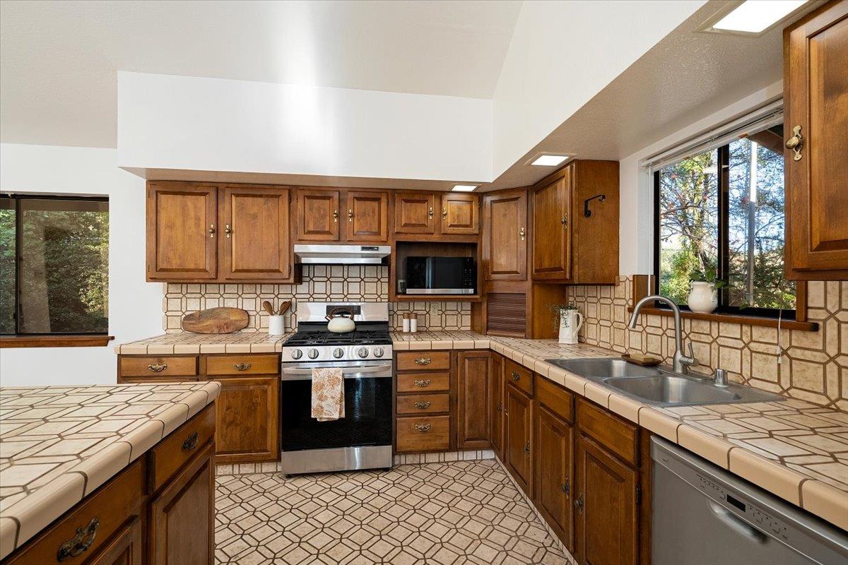 155 Pinewood Way Auburn, CA 95602 - Photo 14 of 92 a kitchen with stainless steel appliances granite countertop a stove top oven a sink dishwasher a dining table and chairs with wooden floor
