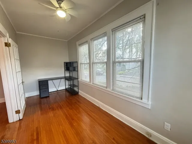 a view of empty room with wooden floor and fan