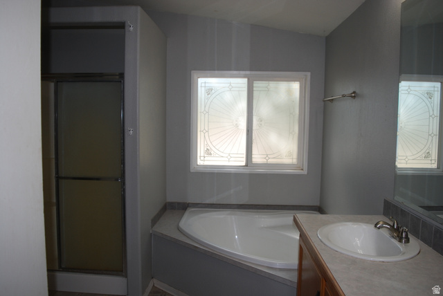 1055 West Ashby Road Delta, UT 84624 - Photo 33 of 44 Bathroom featuring a built-in corner tub, a single vanity with an oval sink, an integrated countertop, and a sliding glass shower enclosure