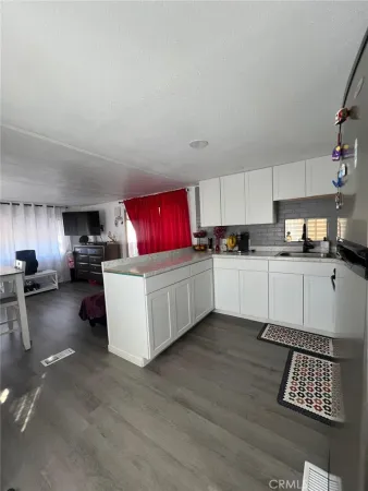 a kitchen with stainless steel appliances kitchen island granite countertop a stove top oven a sink dishwasher and white cabinets with wooden floor