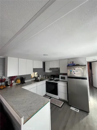 a kitchen with granite countertop stainless steel appliances a sink a stove top oven a counter space and cabinets