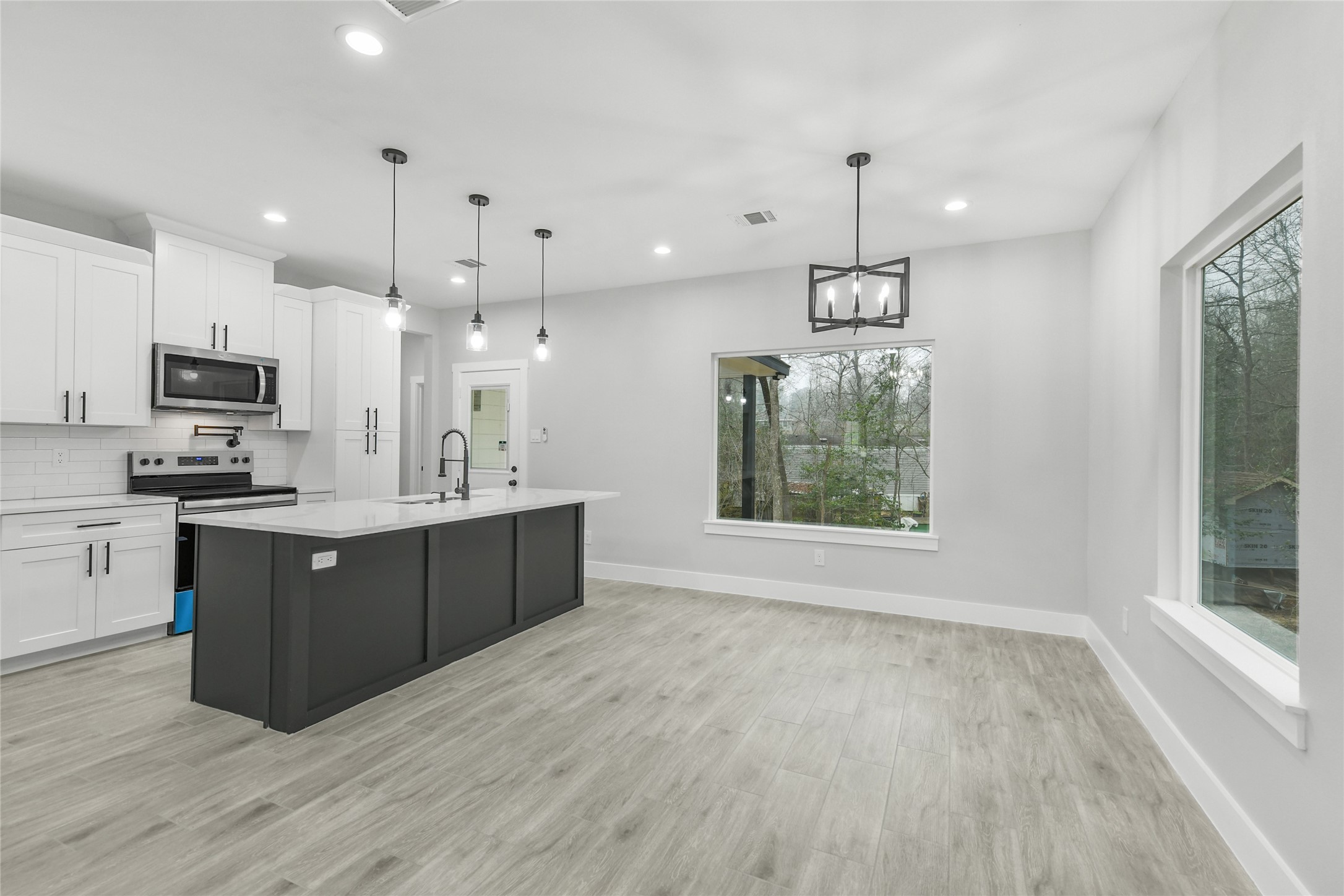 15113 Austin Road Willis, TX 77378 - Photo 8 of 37 a large kitchen with a large center island wooden floor stainless steel appliances and cabinets