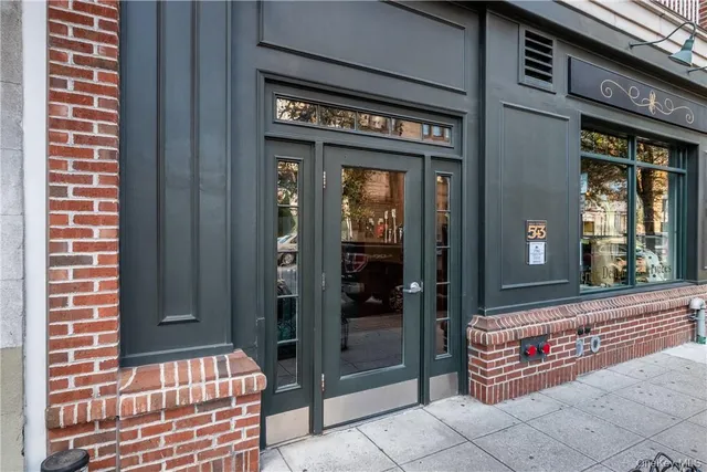 a front view of a building with lot of cars and trees