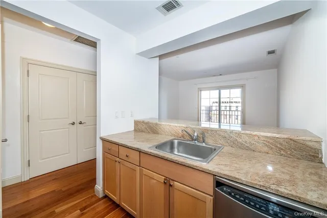 a kitchen with granite countertop stainless steel appliances sink and wooden floor