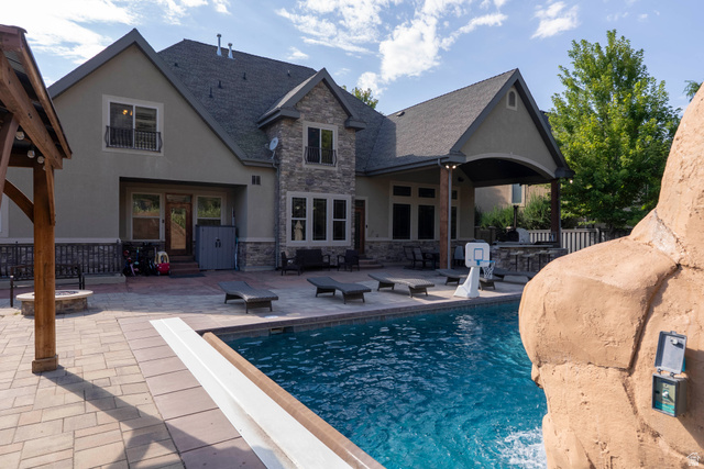 687 South 2080th Street East Springville, UT 84663 - Photo 112 of 149 Stone and stucco exterior featuring a paved patio with an integrated swimming pool, a covered outdoor living area, a stone fire pit, and a built-in outdoor kitchen