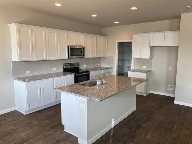 a kitchen with kitchen island granite countertop a sink and steel appliances