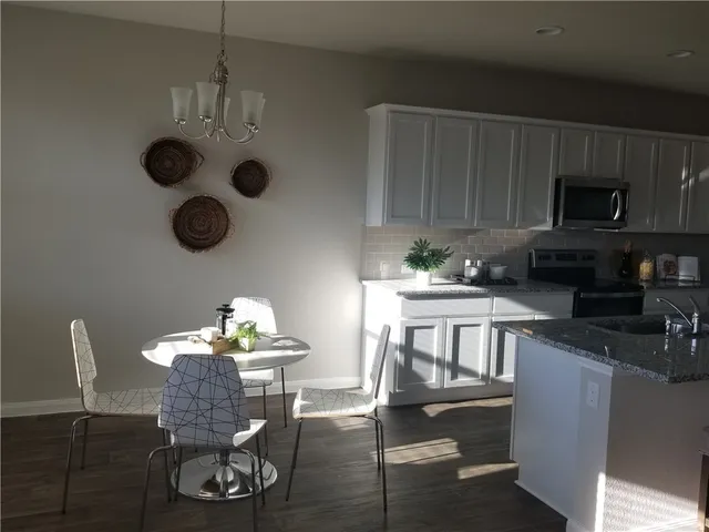 a kitchen with stainless steel appliances granite countertop a dining table and chairs with wooden floor