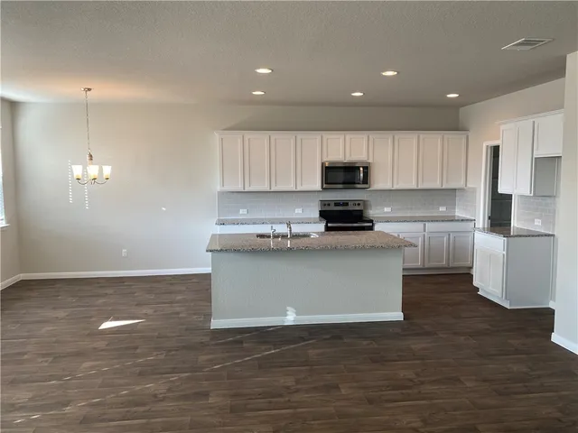 a kitchen with granite countertop a stove a sink and a refrigerator
