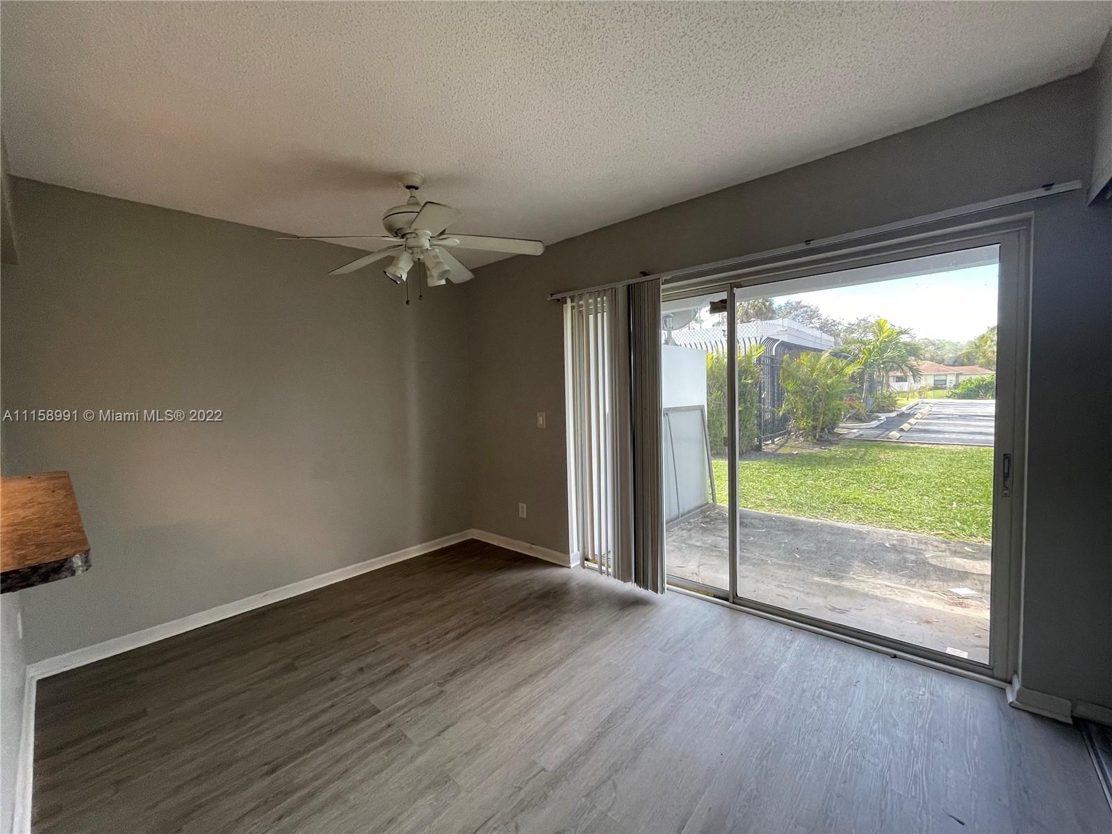 5140 Elmhurst Road, Unit H West Palm Beach, FL 33417 - Photo 4 of 15 a view of an empty room with wooden floor and a window