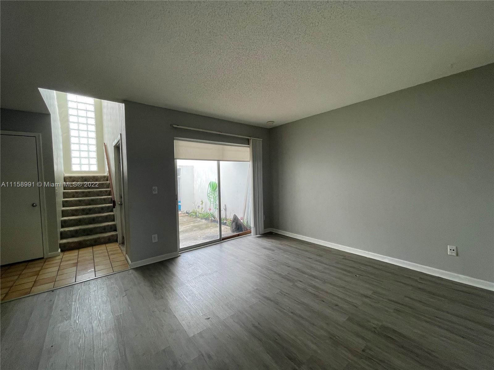5140 Elmhurst Road, Unit H West Palm Beach, FL 33417 - Photo 6 of 15 an empty room with wooden floor and windows