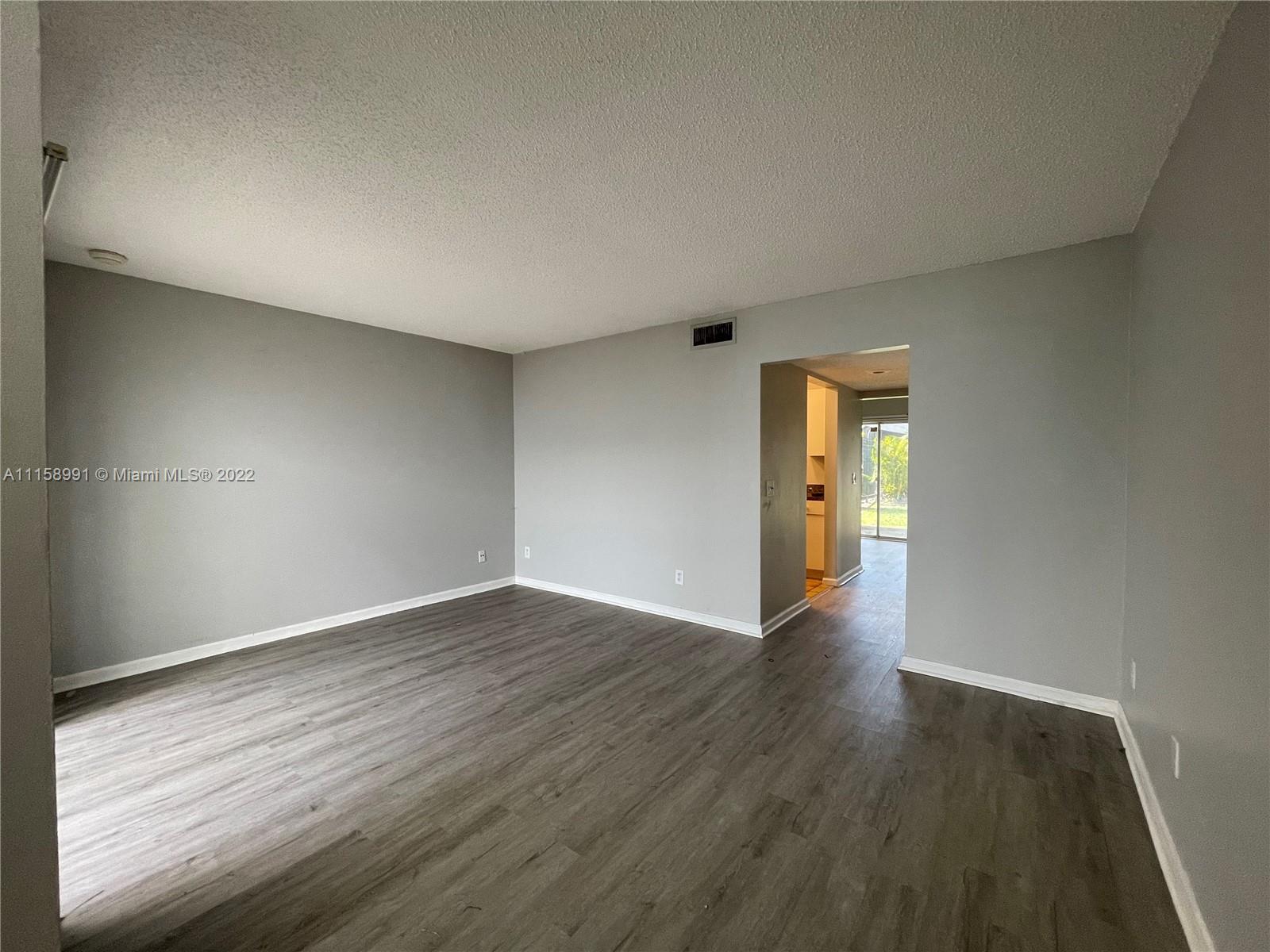 5140 Elmhurst Road, Unit H West Palm Beach, FL 33417 - Photo 7 of 15 a view of an empty room with wooden floor and windows