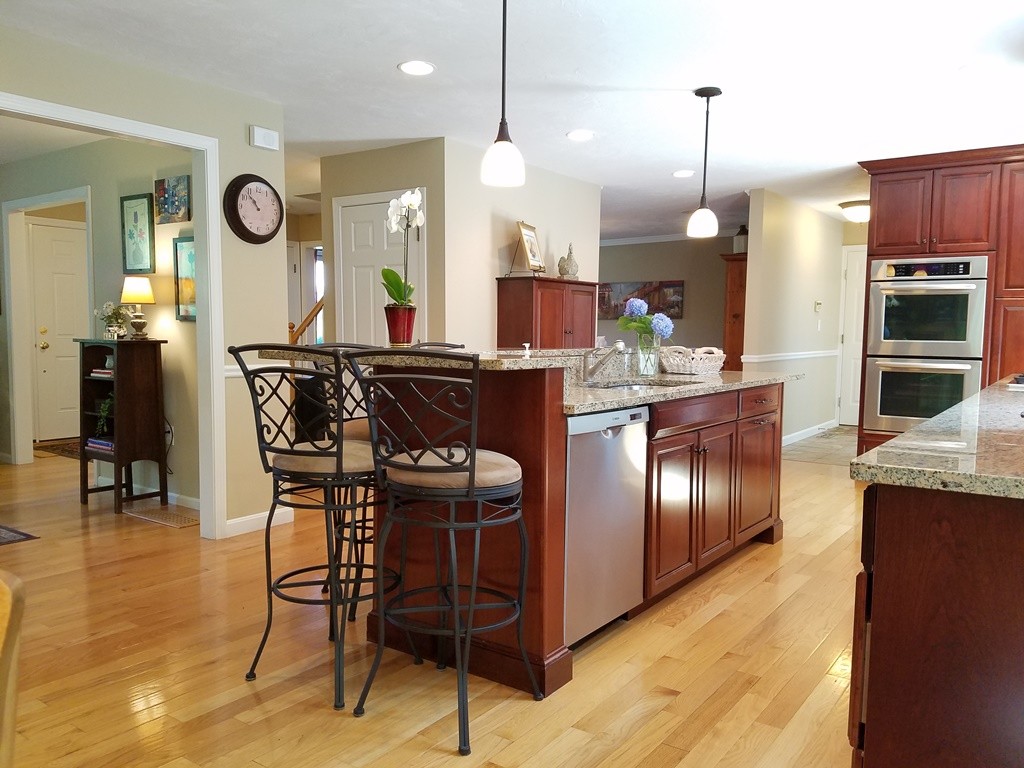 16 Cadorette Road Ashland, MA 01721 - Photo 5 of 29 a kitchen with stainless steel appliances granite countertop a stove a sink a dining table and chairs with wooden floor