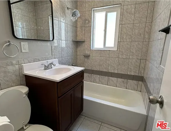 a bathroom with a sink vanity mirror bathtub and toilet